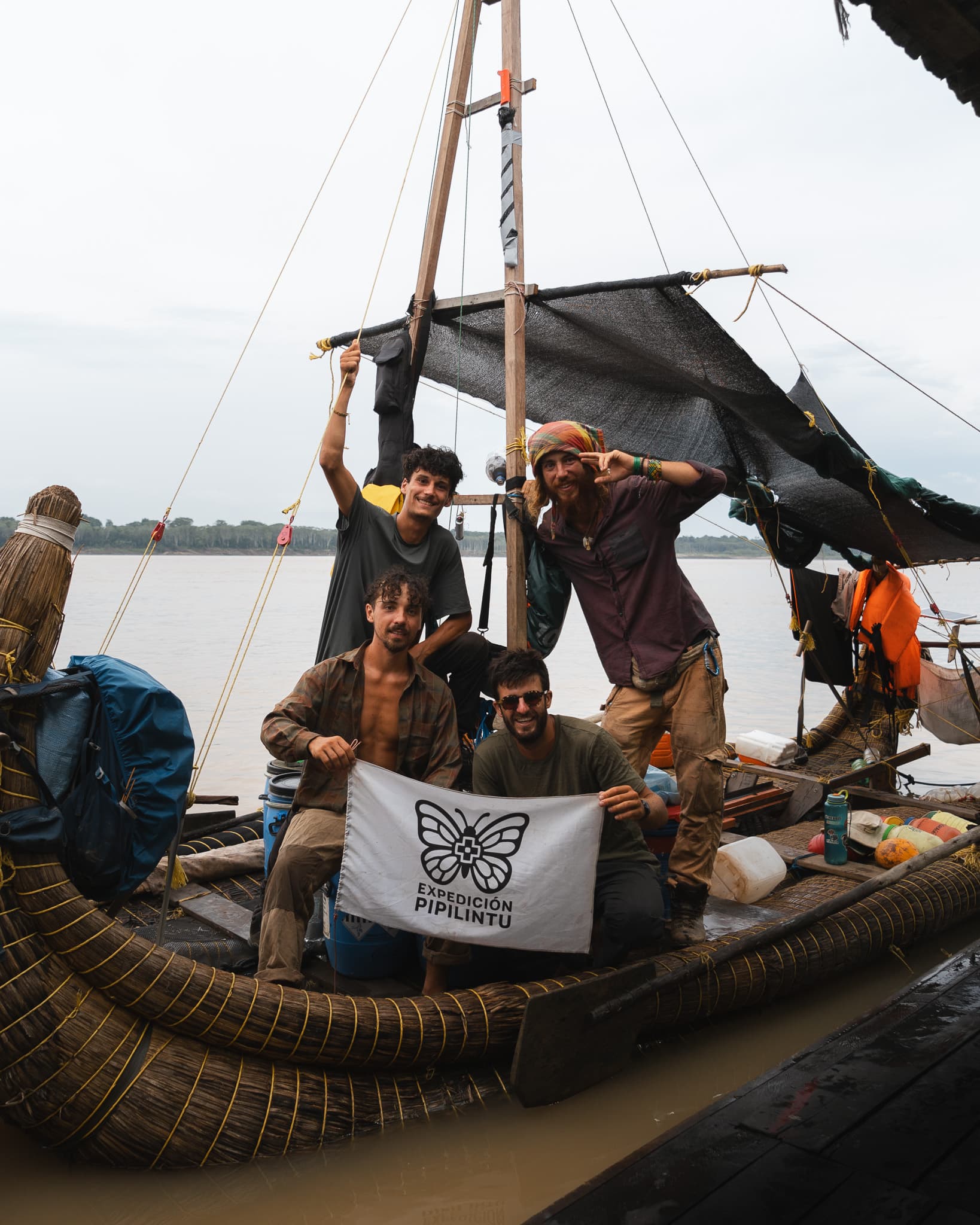 Quatre équipiers posent à bord de la balsa en déployant le drapeau Expedición Pipilintu