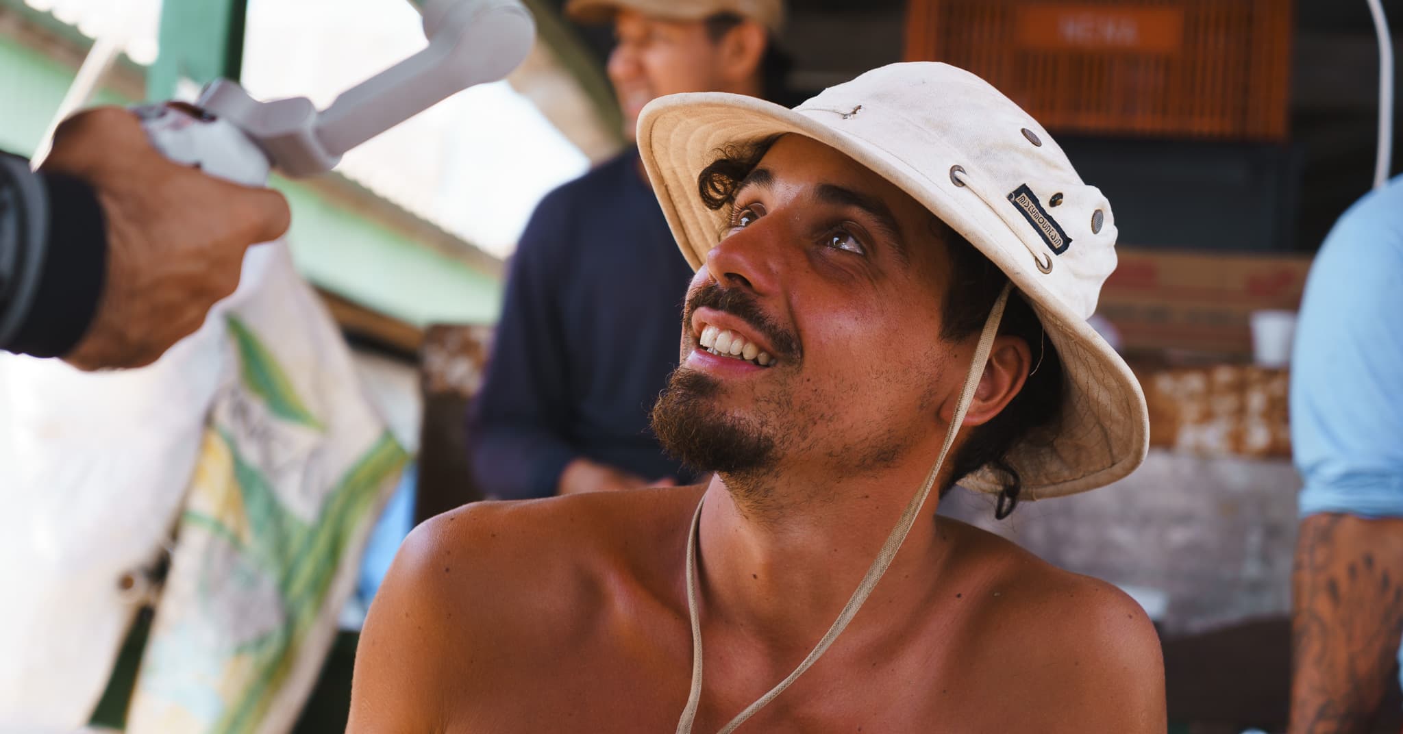 Portrait d'un équipier au chapeau de toile, souriant, lors d'une escale dans un village de rive